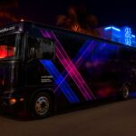 Neon-lit party bus parked on city street at night