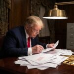 Older man in suit reviewing documents at desk